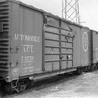 Vintage ACL automobile freight cars on a track.