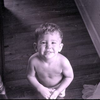 Young child sitting on a wooden floor.