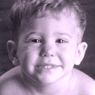 Young child sitting on a wooden floor.