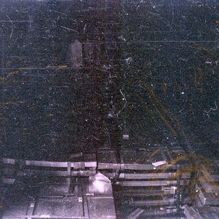 Heavily damaged photo of dark architectural structures.