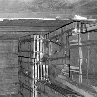 Stacked metal sheets in a concrete storage room.