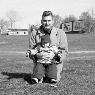 Man and child sitting in a grassy field.