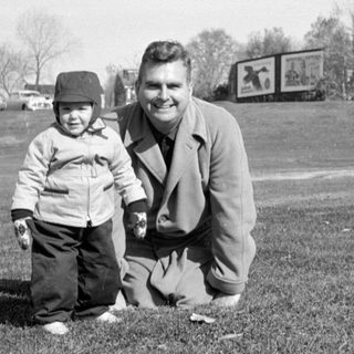 Man and child posing in a grassy field.