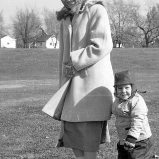 Woman and child standing in a grassy field.