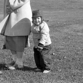 Woman and child standing in a grassy field.
