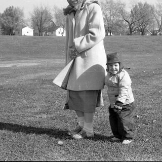 Woman and child standing in a grassy field.