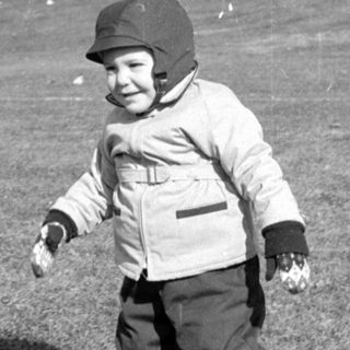 Child in winter clothing standing in a field.