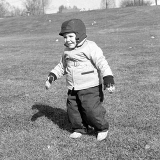 Child in winter clothing standing in a field.