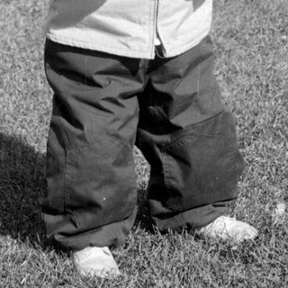 Child in winter clothes holding stones in a field.