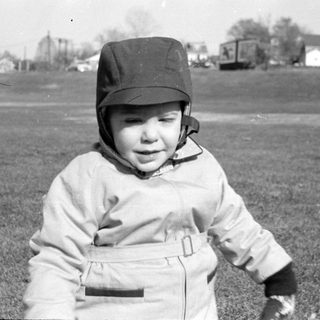 Child in a cap and jacket in a field.
