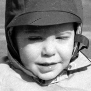 Child in a cap and jacket in a field.