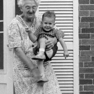 Woman holding a child in a brick house doorway.