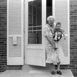 Woman holding a child in a brick house doorway.