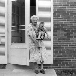 Woman holding a child in a brick house doorway.