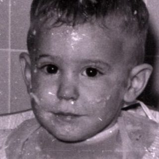 Child in high chair with food on face.