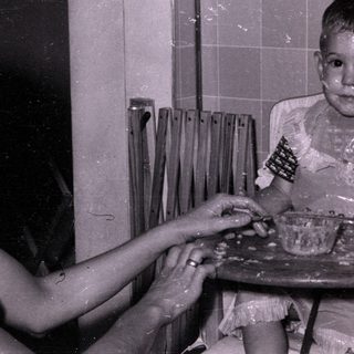 Child in high chair with food on face.