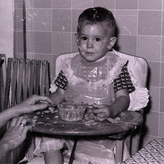 Child in high chair with food on face.