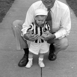 Man and young child posing on a sidewalk.
