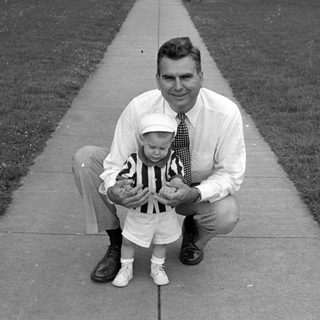 Man and young child posing on a sidewalk.