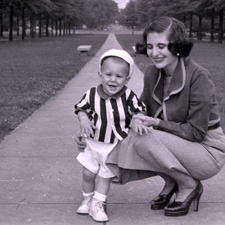 Woman and young boy in striped shirt on walkway.