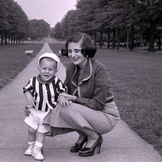 Woman and young boy in striped shirt on walkway.