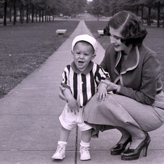 Woman and child on a tree-lined path.