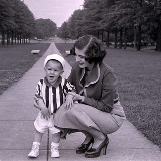 Woman and child on a tree-lined path.