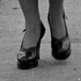 Child in striped shirt walking before large building.