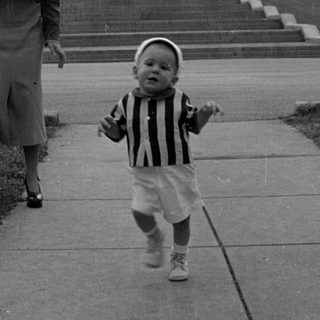 Toddler and woman in front of stone collegiate building.