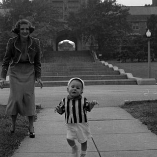 Toddler and woman in front of stone collegiate building.