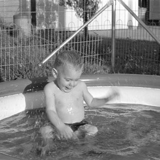 Young child splashing in an inflatable swimming pool.