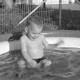Young child splashing in an inflatable swimming pool.