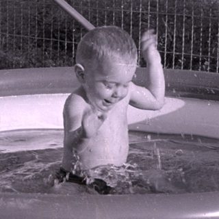 Child playing in an inflatable pool outdoors.