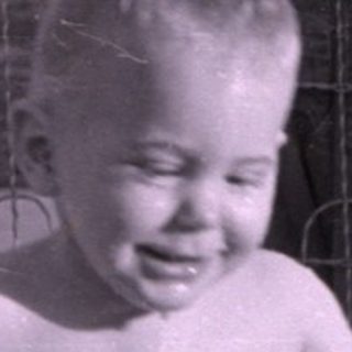 Child standing in an inflatable swimming pool.
