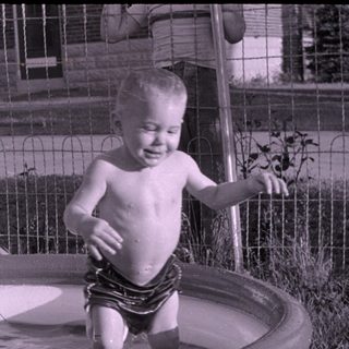 Child standing in an inflatable swimming pool.
