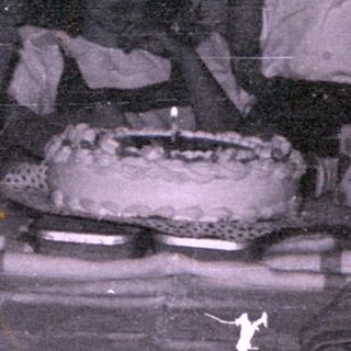 Group of people gathered around a cake.