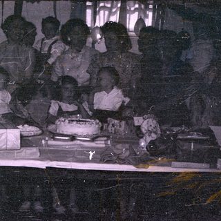 Group of people gathered around a cake.