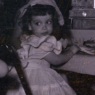 Two children in bonnets at a table with adults.