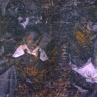 Severely degraded photo with fragmented figures and staining.