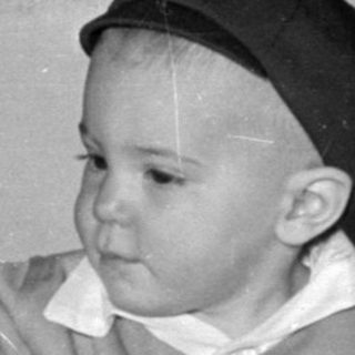Child in a cap sitting behind a cake.