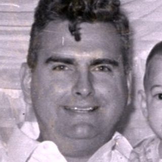 Man and baby sitting on a patterned sofa.