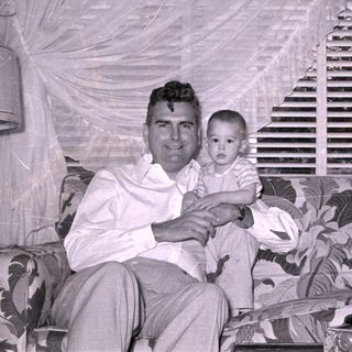 Man and baby sitting on a patterned sofa.
