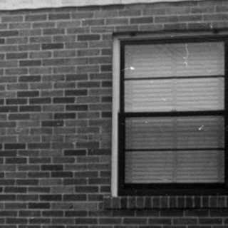 Man holding an infant in front of brick house.