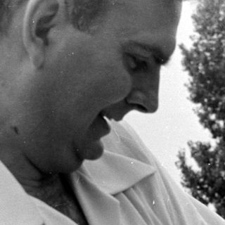 Man in white shirt holding a sleeping infant.