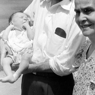 Man and woman holding a baby outdoors.
