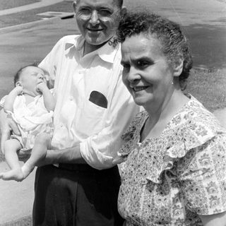 Man and woman holding a baby outdoors.