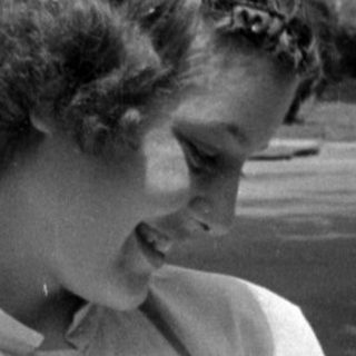 Woman holding an infant outdoors in black and white.