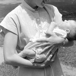 Woman holding an infant outdoors in black and white.