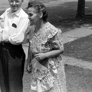 Man and woman with an infant on a sidewalk.
