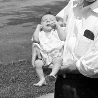 Man and woman with an infant on a sidewalk.